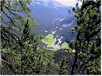 Hotel Il fuorn and the Pass dal Fuorn road seen through the forest near Alp Grimmels