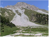 Val da Stabelchod - an alpine meadow in the foreground and a rough mountain in the back