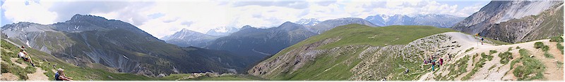 Panoramic view from Margunet - some hikers on Margunet on the left, a whole mountain range in the background, more hikers just arriving on Margunet on the right