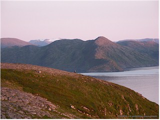 [ kste bei hammerfest kurz nach mitternacht mit schneebedeckten bergen im hintergrund ]