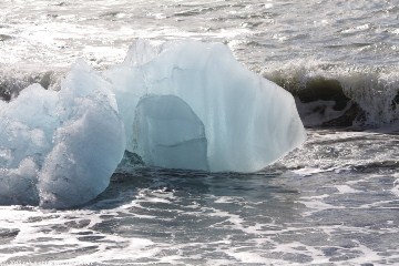 eisblock aus dem joekulsarlon in den wellen am strand
