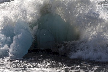 eisblock aus dem joekulsarlon unter einer welle am strand