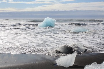 eisblock aus dem joekulsarlon in den wellen am strand
