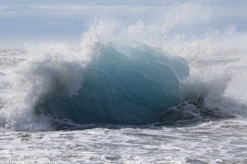 eisblock aus dem joekulsarlon unter einer welle am strand
