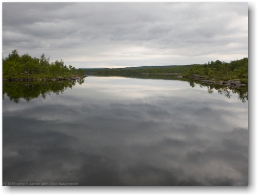 dunkle wolken spiegeln sich im lutaure im pieljekaise nationalpark